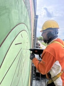 Het ophangen van de schaduwwerper voor de muurschildering zonnewijzer te Utrecht