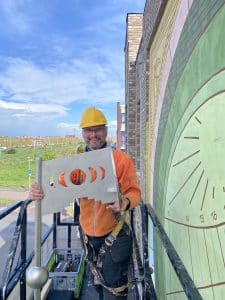 De schaduwwerper van RVS voor de zonnewijzer op de muurschildering te Utrecht