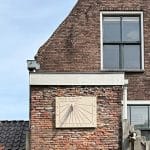 Zonnewijzer van zandsteen aan de muur van een binnentuin