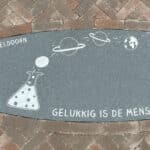 Bij de zonnewijzer ligt een ovale stenen plaat met tekeningen van de leerlingen van Gymnasium Apeldoorn
