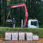 Met de hijskraan worden de stenen voor het zonnewijzerplein nabij de stelplaats gelegd